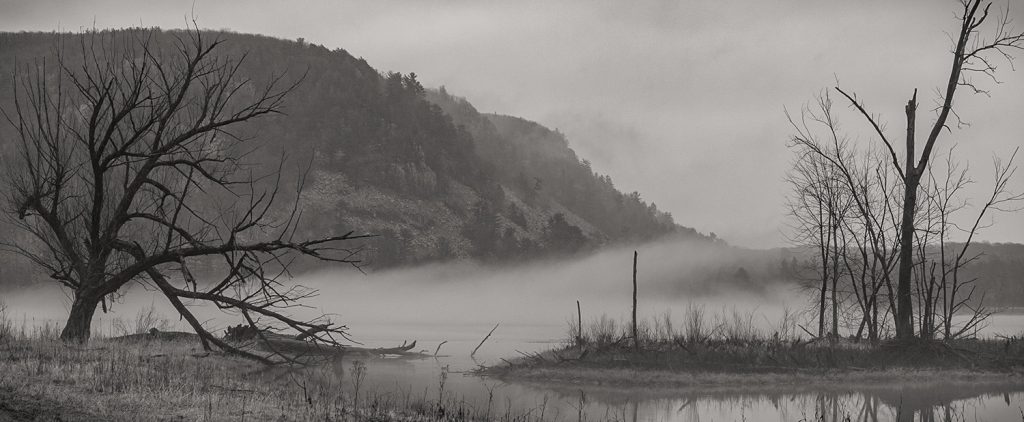 Greyscale image of lake with hills in the back